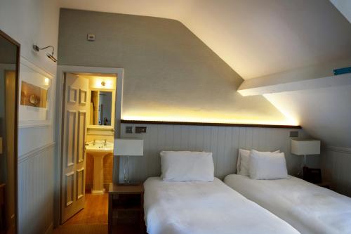 two beds in a room with a hallway with a sink at Trearddur Bay Hotel in Trearddur