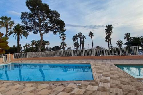 une piscine avec une clôture et des palmiers dans l'établissement Vue mer exceptionnelle-piscine, à Saint-Raphaël