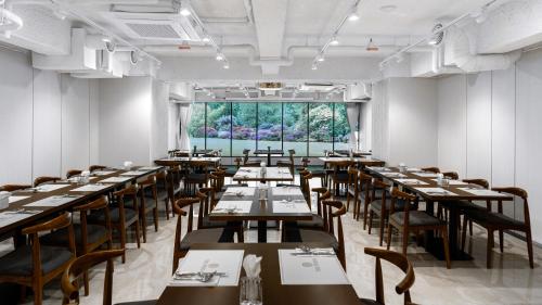 uma sala de jantar com mesas e cadeiras e uma grande janela em The Prima Hotel Jongno em Seul