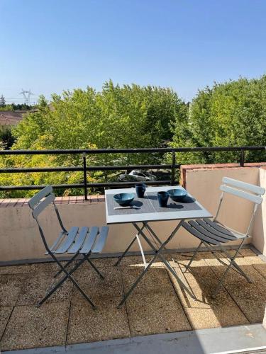 une table et deux chaises assises sur un balcon dans l'établissement Studio Cosy Elancourt, Les terrasses d'Héricé, à Élancourt