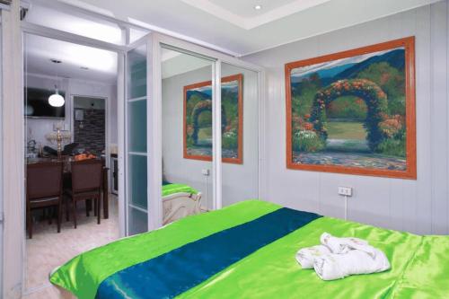 a bedroom with a green bed and a painting at Golden V Grandeuria Unit E in Malolos