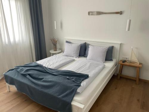 a white bed with a blue blanket on top of it at Pannonia Apartments in Mörbisch am See