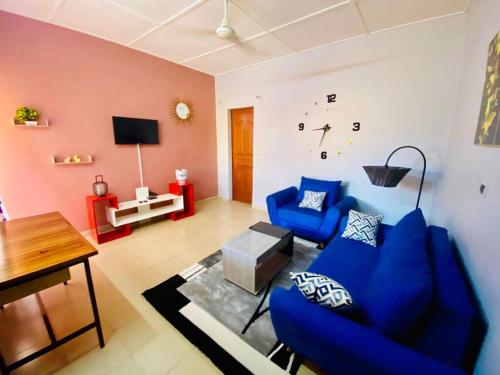 a living room with blue chairs and a clock on the wall at Eden Meublé in Ouagadougou