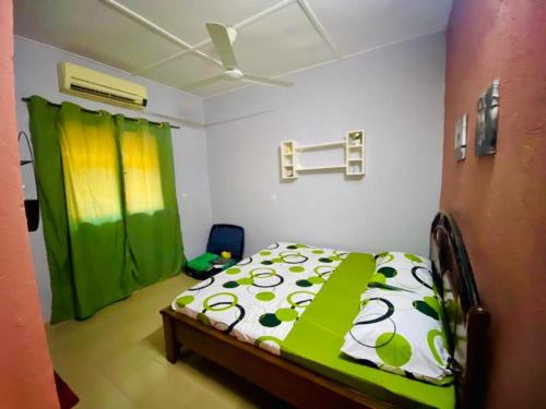 a bedroom with a bed with a green and white comforter at Eden Meublé in Ouagadougou