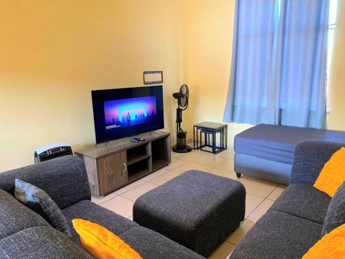 a living room with a couch and a flat screen tv at Royal Taste of Africa Apartments in Windhoek