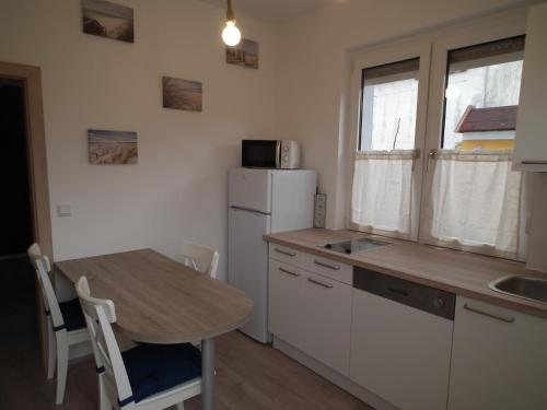 eine Küche mit einem Tisch und einem weißen Kühlschrank in der Unterkunft Appartement blue Dinghi in Mörbisch am See