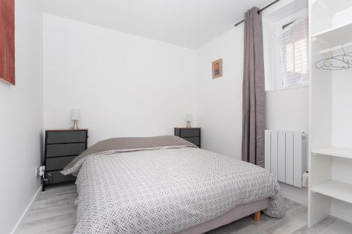 een witte slaapkamer met een bed en een raam bij Côté Jardin 2 - Appartement avec Jardin in Le Coteau