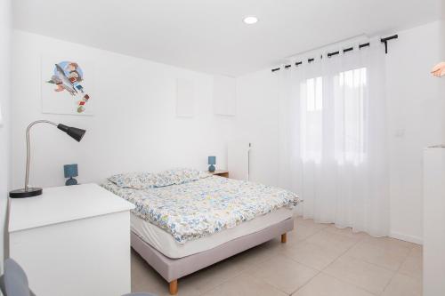 Dormitorio blanco con cama y lámpara en Côté jardin 1 - Appartement avec Jardin, en Le Coteau