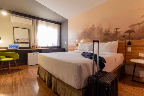 a hotel room with a bed and a suitcase at Hotel Cassino Tower Curitiba Aeroporto By Nacional Inn in São José dos Pinhais