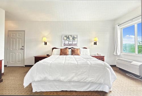 a white bedroom with a large white bed and a window at Gasthof Amish Village INN in Montgomery