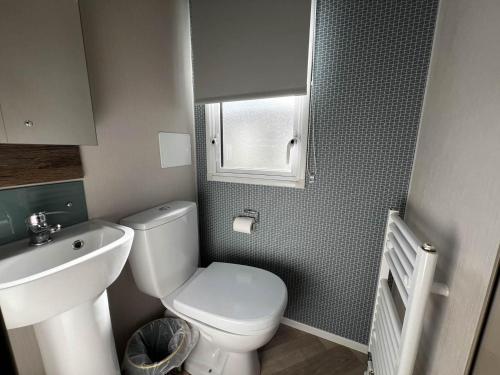 a small bathroom with a toilet and a sink at Stunning Caravan With Decking At Azure Seas In Suffolk Ref 32055az in Lowestoft