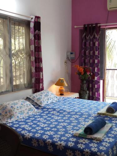 een slaapkamer met een bed met een blauw dekbed bij Casa Baptista Guest House in Goa