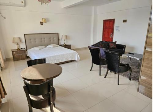 Hotel Kilimanjaro - Luanda Angola في لواندا: غرفة نوم بسرير وطاولة وكراسي