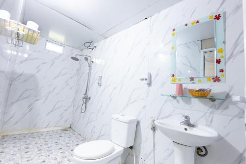 a white bathroom with a toilet and a sink at Cat Ba Countryside Homestay in Cat Ba