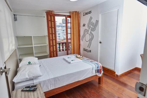 Habitación pequeña con cama y mesa en Hostel Prada en Lima