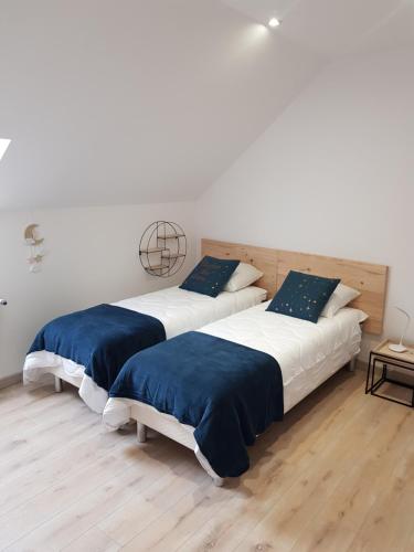 Habitación blanca con 2 camas y suelo de madera. en Mon Gîte en Château-du-Loir