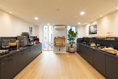 a large kitchen with black cabinets and a wooden floor at Fred Guest House Zürich Hauptbahnhof in Zurich