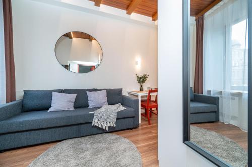 a living room with a blue couch and a mirror at Cozy studio in the city center in Vilnius