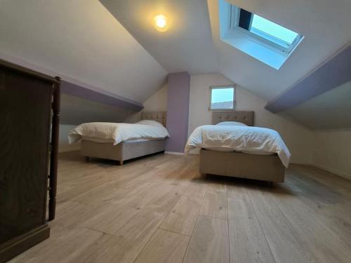 a attic bedroom with two beds and a skylight at Maison RNA spacieuse 5 chambres in Saint-Witz