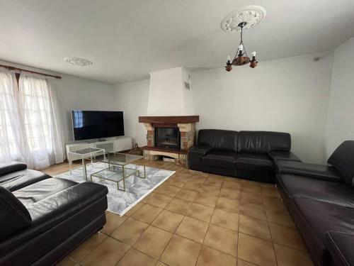 ein Wohnzimmer mit einem schwarzen Ledersofa und einem Kamin in der Unterkunft Maison RNA spacieuse 5 chambres in Saint-Witz