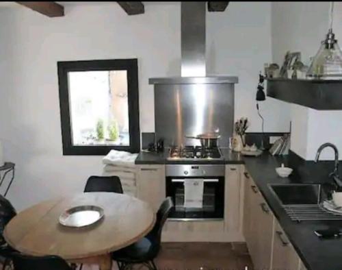 eine Küche mit einem Tisch, einem Herd, einem Tisch und einem Fenster in der Unterkunft Grande maison en pierre dans la colline varoise in Vidauban