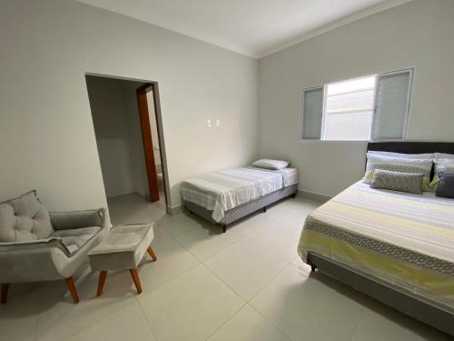 Un dormitorio con 2 camas y una silla. en Casa bem Equipada 3 quartos, en Marília