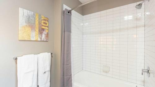 y baño con ducha y bañera de azulejos blancos. en Luxury Apartment In Harbor Point, en Stamford