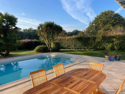 um pátio com uma mesa e cadeiras e uma piscina em Villa 4 étoiles sur le Golf Makila près de Biarritz em Bassussarry