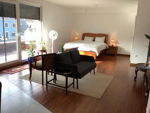 uma sala de estar com uma cama, um sofá e uma mesa em Sanhe em Mersch