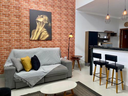 a living room with a couch and a brick wall at Casa bem Equipada 3 quartos in Marília