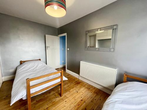 a bedroom with two beds and a mirror on the wall at Greater London House with excellent transport in Forest Hill