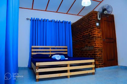 1 dormitorio con 1 cama con cortinas azules y pared de ladrillo en Mereiyans Village Villa, en Ampara