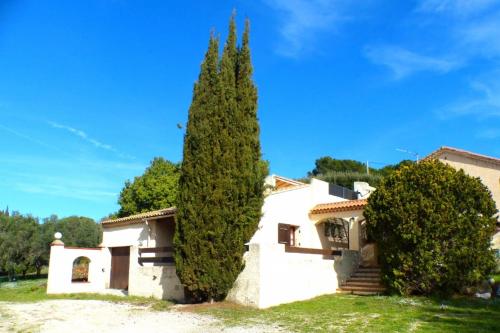 une maison avec un grand arbre en face dans l'établissement Family cottage facing the sea, à Six-Fours-les-Plages