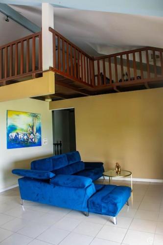 un soggiorno con divano blu e scala di Villa Orchidée, à la découverte du nord a Le Lorrain