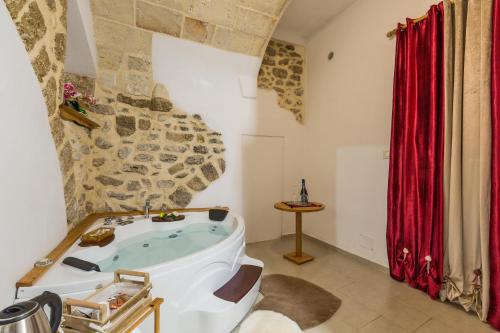 a bathroom with a tub in a room with a stone wall at Casa Relax in Mesagne