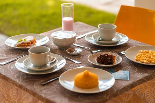 a table with plates of food and cups of coffee at Apprezzare . Pousada beira-mar in Porto De Galinhas