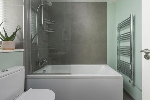 een badkamer met een wit bad en een douche bij Salt Life, Dunes at Upton Towans in Hayle