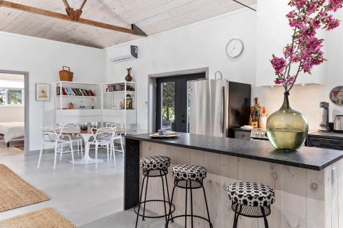 a kitchen with a counter with stools and a vase with flowers at The Barns of Brighton Near Prince Edward County in Brighton