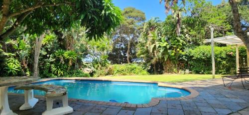 a swimming pool with a table and a bench in a yard at Seacastle Guesthouse in Port St Johns