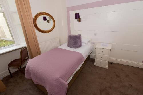 a small bedroom with a bed and a mirror at Steeton Hall Hotel & Restaurant in Steeton