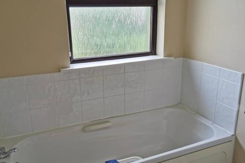 y baño con bañera y ventana. en Bungalow by the Beach, en Tramore