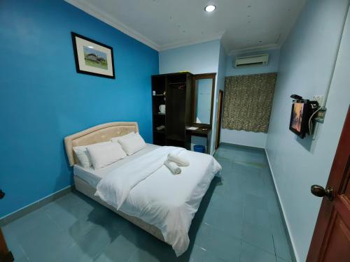 a blue bedroom with a bed with white sheets at Marang Village Resort in Marang