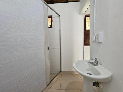 a white bathroom with a sink and a shower at Casa Grande Surf in Guachaca