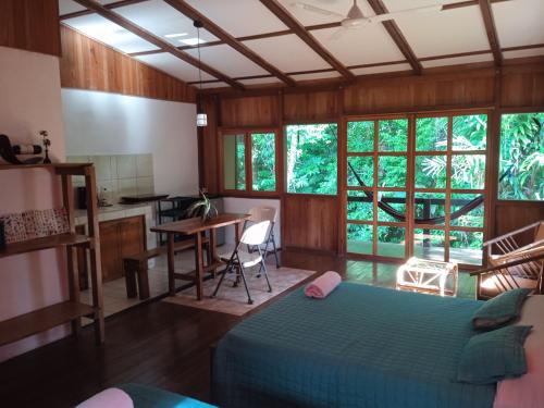 a bedroom with a bed and a table and a kitchen at Cabañas Bajo Bosque Drake in Drake