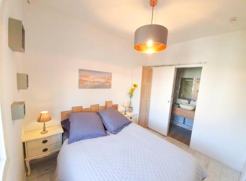 une chambre avec un lit blanc avec des oreillers bleus dans l'établissement Studio 28m2 avec balcon, très proche de la mer, à Saint-Laurent-du-Var