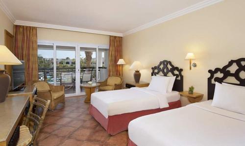 a hotel room with two beds and a balcony at Double room with garden in Sharm El Sheikh