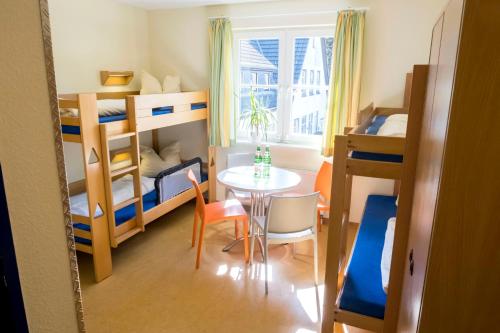 a small room with a table and bunk beds at Jugendherberge Friedrichstadt in Friedrichstadt