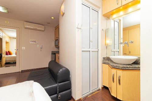 uma casa de banho com uma cadeira de couro preto e um lavatório em Vossa Bossa Bela Cintra em São Paulo