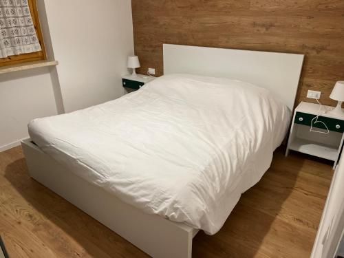 uma cama branca num quarto com duas mesas de cabeceira em Casetta nel bosco - Appartamento "Le betulle" Lavarone em Chiesa