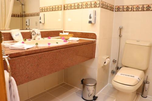 uma casa de banho com um lavatório, um WC e um espelho. em MG Alexander The Great Hotel em Marsa Alam